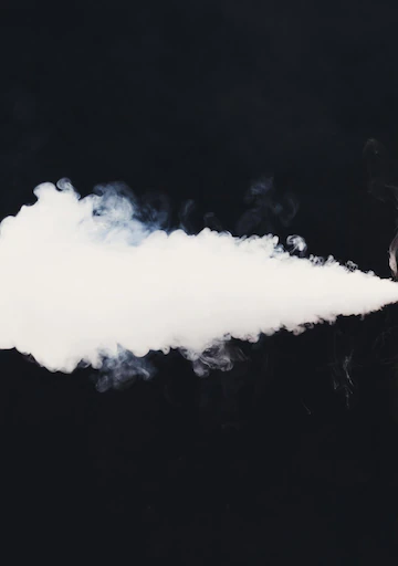 mała chmura z e-papierosa, vaper wydmuchujący mało pary, jednorazowy vape słaba chmura - Biały dym vape z e-papierosa na czarnym tle. Koncepcja palenia bez ...